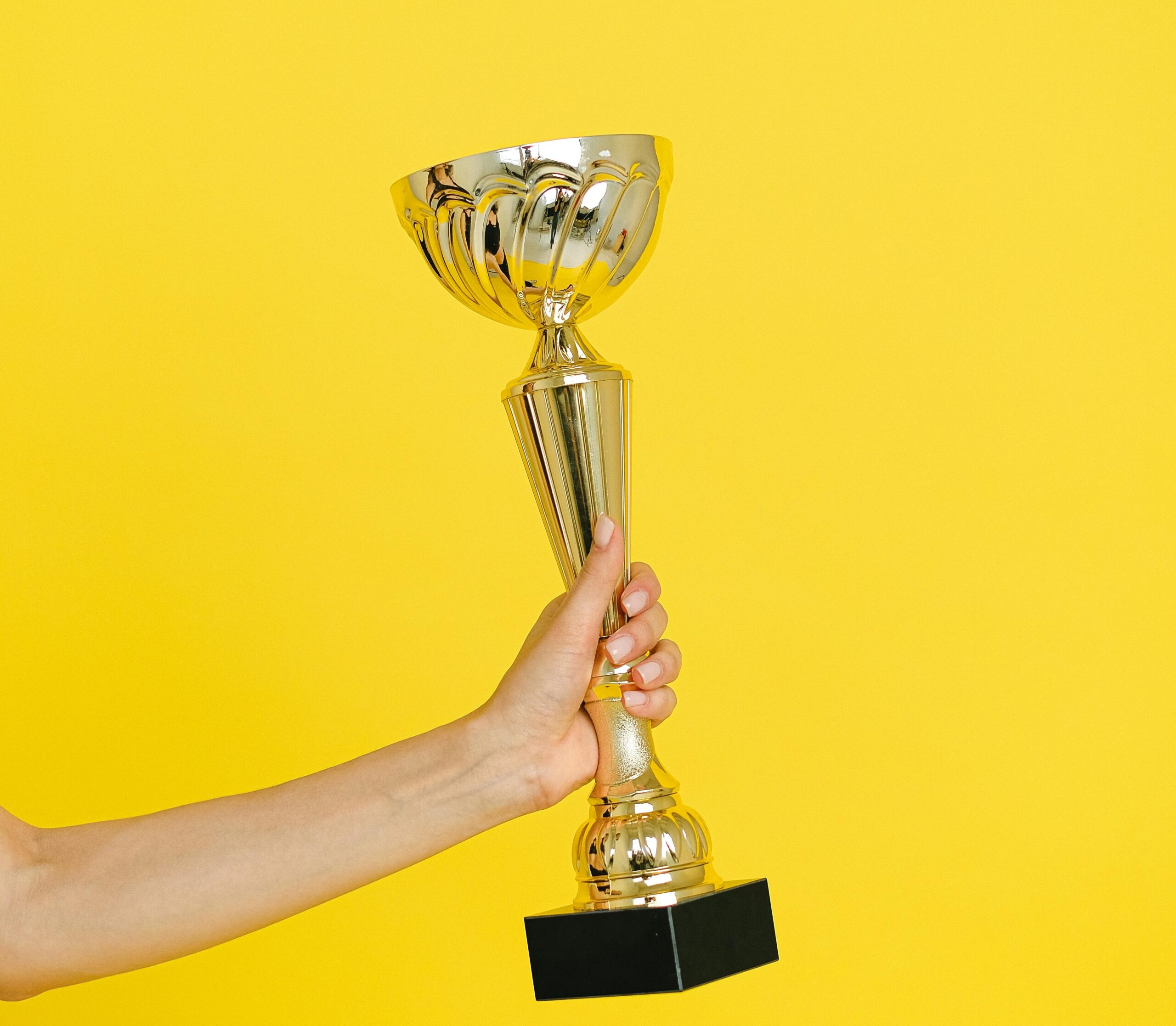 Close-up of a shiny gold trophy on a wooden stand, representing achievement, success, and victory.